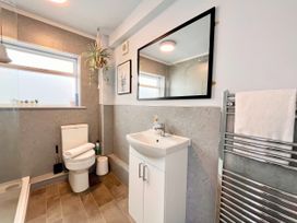 A bathroom with a toilet, vanity, and mirror at Clarence House in Llandudno