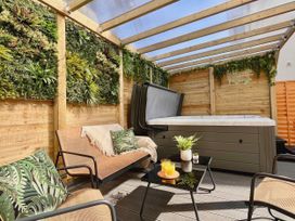 An outdoor patio with a hot tub, seating area, and plant wall at Clarence House in Llandudno
