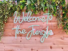 A neon sign with greenery on a wooden wall at Clarence House in Llandudno