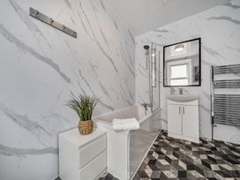 A bathroom with a bathtub, sink, and mirror at Clarence House in Llandudno