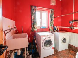 A laundry room with two machines and a utility sink at Clwyd Special Riding Centre