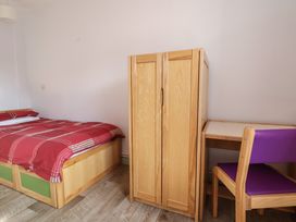 A bedroom with a bed, wardrobe, desk, and chair at Clwyd Special Riding Centre