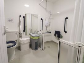 A bathroom with a toilet, shower area, and handrails at Clwyd Special Riding Centre