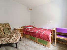 A bedroom with a bed and an armchair at Clwyd Special Riding Centre