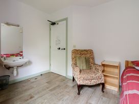 A bedroom with a bed, chair, and sink at Clwyd Special Riding Centre in 