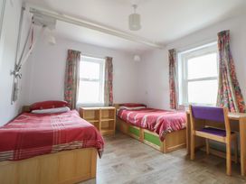 A bedroom with two beds and a chair at Clwyd Special Riding Centre