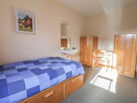 A bedroom with a bed, chair, and wardrobe at Clwyd Special Riding Centre