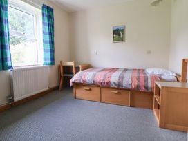 A bedroom with a bed and chair at Clwyd Special Riding Centre