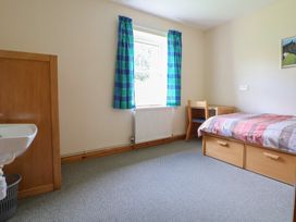 A bedroom with a bed, desk, chair, and sink at Clwyd Special Riding Centre