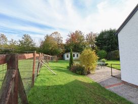 A garden with a shed, table, and chairs at Clwyd Special Riding Centre
