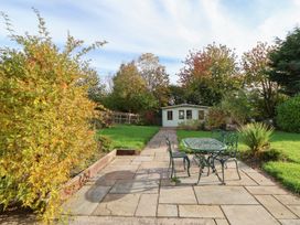 A garden with a table and chairs in a patio area at Clwyd Special Riding Centre