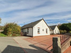 An outdoor view of a building with a pathway and flowering shrubs at Clwyd Special Riding Centre