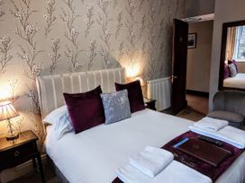 A bedroom with a bed, pillows, and a nightstand at 1 Park Road in Windermere