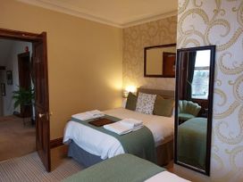 A bedroom with a bed, mirror, and chair at 1 Park Road Windermere