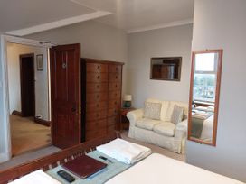 A bedroom with a bed, wardrobe, sofa and window at 1 Park Road, Windermere