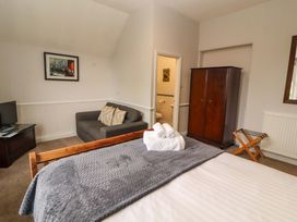 A bedroom with a bed, sofa, and television at 1 Park Road, Windermere