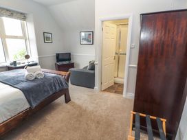 A bedroom with a bed, sofa, and television at 1 Park Road, Windermere