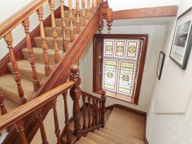 A staircase with wooden handrail and stained glass window at 1 Park Road Windermere
