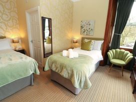 A bedroom with two beds and a mirror at 1 Park Road in Windermere