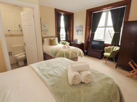 A bedroom with two beds and an armchair at 1 Park Road Windermere