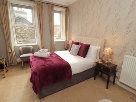 A bedroom with a bed and chair at 1 Park Road in Windermere