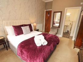 A bedroom with a bed, chair and bathroom at 1 Park Road Windermere