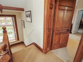A hallway with a stained glass window and wooden doors at 1 Park Road Windermere