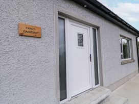 An entrance with a white door and a wooden sign at Teach Caoimhe in Falcarragh