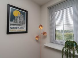A room featuring a poster, floor lamp, window, and plant at Larpool Retreat