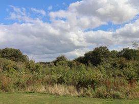An outdoor area with grass, trees, and bushes under a cloudy sky at Larpool Retreat 