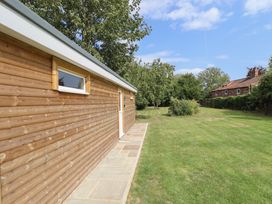 A wooden building exterior with a pathway in the garden at Pear Tree Lodge in Alford