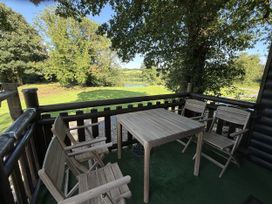 An outdoor seating area with a table and chairs overlooking a pond at Oak Lodge Mynydd Cerrig near Porthyrhyd