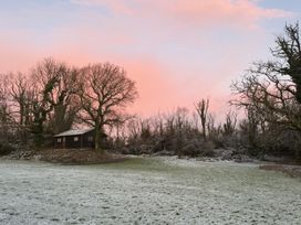 A wooden house surrounded by trees in a snowy field at Oak Lodge near Mynydd Cerrig