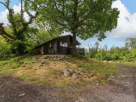 A cabin surrounded by trees and a rocky path at Oak Lodge in Mynydd Cerrig near Porthyrhyd