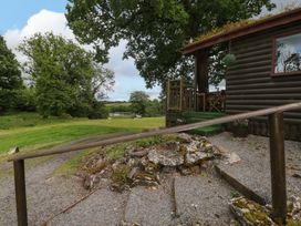 An outdoor view of a cabin with a deck and gravel path at Oak Lodge in Mynydd Cerrig near Porthyrhyd