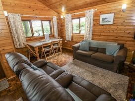 A living room with a sofa and dining table at Oak Lodge Mynydd Cerrig near Porthyrhyd