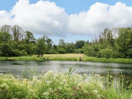 A scenic view of a lake with fishing and greenery at Oak Lodge, Mynydd Cerrig near Porthyrhyd