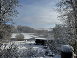 A snowy landscape featuring a lake and a cabin at Ash Lodge near Mynydd Cerrig Porthyrhyd