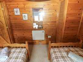 A bedroom with two beds and wooden walls at Ash Lodge near Mynydd Cerrig near Porthyrhyd