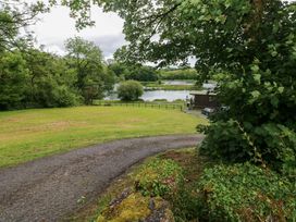 A lake view with trees and a cabin at Ash Lodge in Mynydd Cerrig near Porthyrhyd
