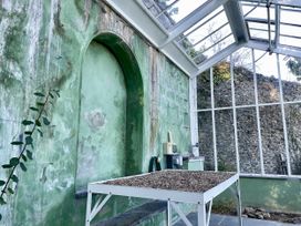 A greenhouse with a table of gravel and green walls at West Cottage Myddfai near Llandovery