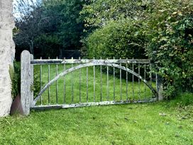 A gate leading to a grassy area with bushes and trees at West Cottage Myddfai near Llandovery