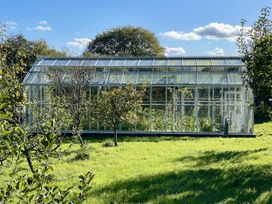 A greenhouse with plants surrounded by grass at West Cottage in Myddfai near Llandovery