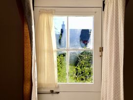 A window with a curtain showing greenery at West Cottage in Myddfai near Llandovery