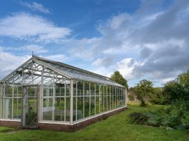 A greenhouse with plants and a door at West Cottage in Myddfai near Llandovery