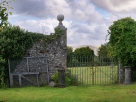 A gate with a stone wall and grass at Gatekeepers Cottage in Llandovery