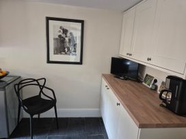 A kitchen with a chair, television and kettle at Gatekeepers Cottage near Llandovery