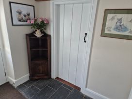 An entryway with a wooden shelf and flowers at Gatekeepers Cottage in Myddfai near Llandovery
