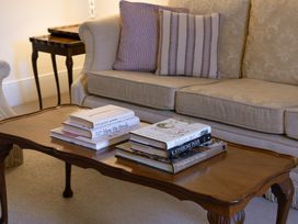 A living room with a sofa and coffee table stacked with books at Gatekeepers Cottage Myddfai near Llandovery