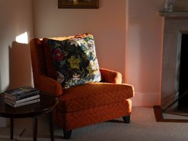 A living room with an armchair and a table with books at Gatekeepers Cottage Myddfai near Llandovery